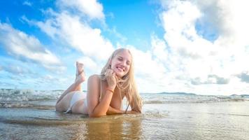 porträtt av en vacker blond kvinna njuta av sin sommartid på stranden. foto