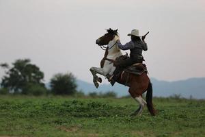 cowboy ridhäst med hand som håller pistol mot solnedgången bakgrund. foto