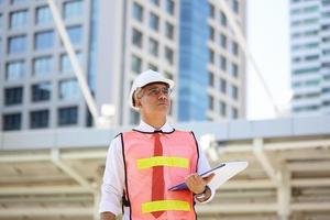 ingenjören kollar på urklipp på byggarbetsplatsen. begreppet teknik, byggande, stadsliv och framtid. foto