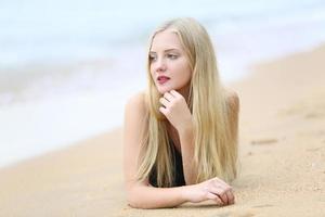 vacker blond kvinna på svart bikini njuta av sommaren på stranden. foto