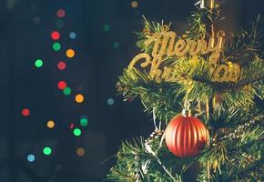 vackert juldekorationskoncept, grannlåt som hänger på julgranen med gnistrande ljusfläck, suddig mörk svart bakgrund, makrodetalj, närbild. foto