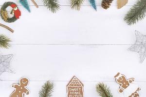 julkoncept sammansättning dekorationsobjekt, gran gren krans, pepparkaksman kex isolerad på vitt träbord, ovanifrån, platt lay foto