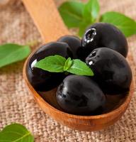 svarta oliver på ett träbord foto