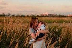 en mamma går på fältet med sin lilla dotter i famnen. foto