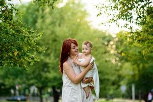 mamma kramar och leker med sin ettåriga dotter inlindad i en handduk efter att ha badat. foto