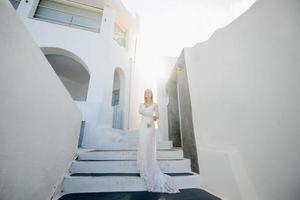 det vackra blonda håret unga kvinnor bruden blå i en vit lång sexig klänning för bröllop på santorini i Grekland foto