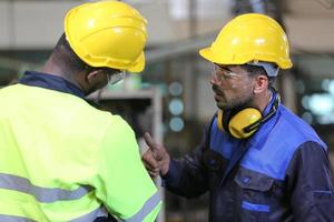 underhållsingenjörer arbetar framför den automatiska reparationen av cnc-maskiner på en checklista för underhåll vid produktionslinjen. foto