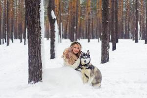 glada nygifta par går på stigen i den snöiga skogen med två sibiriska hundar. vinterbröllop. konstverk. kopieringsutrymme foto