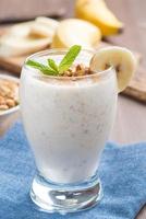 milkshake med banan, granola och kanel i ett glas, vertikalt foto