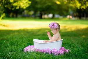 liten flicka badar i ett mjölkbad i parken. flickan har roligt på sommaren. foto