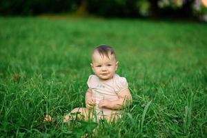 liten ettårig flicka sitter på gräset. foto