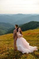 eleganta unga bruden och brudgummen står i båten på bakgrunden moln himmel havet och bergen i montenegro foto