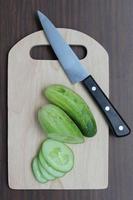 gurka slicer kniv på en skärbräda foto