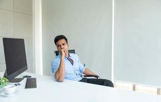 asiatisk attraktiv affärsman som tänker på affärsekonomin och företagets framtid i det moderna kontoret foto