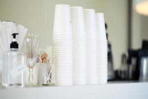 selektivt fokus på den första stapeln av vita pappersmuggar på bordet på kaféet foto