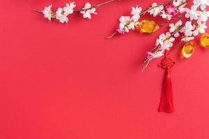 designkoncept av kinesiska månnyåret - vacker kinesisk knut med plommonblomning isolerad på röd bakgrund, platt låg, ovanifrån, overhead layout. foto