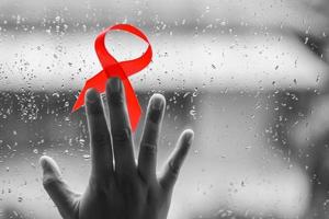 rött band på händerna för hjälpmedel och cancer kampanj bakgrund foto