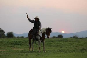 cowboy till häst mot en vacker solnedgång, cowboy och häst vid första ljuset, berg, flod och livsstil med naturligt ljus bakgrund foto