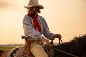 cowboy till häst mot en vacker solnedgång, cowboy och häst vid första ljuset, berg, flod och livsstil med naturligt ljus bakgrund foto