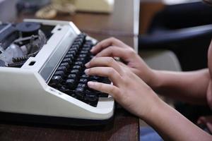 närbild på kvinnor hand att skriva på skrivmaskin. foto