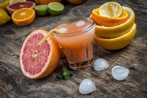 saftglas och färsk citrusfrukt på rustikt trä foto