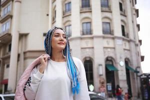 porträtt av ung flicka med blått hår, tonåring som står på gatan som stadsliv. foto