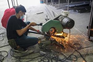 svetsare använde slipsten på stål i fabrik med gnistor, svetsprocess på industriverkstaden, händer med instrument i ram. foto