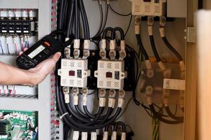 elektriker ingenjör arbetsprovare som mäter spänning och ström för kraftledning i elskåpsstyrning. foto