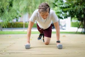 aktiv asiatisk idrottsman gör en kroppsviktsövning, man gör push up-träning med hantel. intensiv träning för bodybuilding. foto