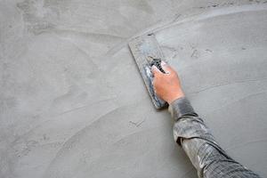 putsare man hand med murslev för att putsa cement på betongvägg bakgrund på byggarbetsplatsen foto