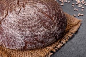nybakat hembakat brunt bröd på en svart betongbakgrund med vetekorn foto