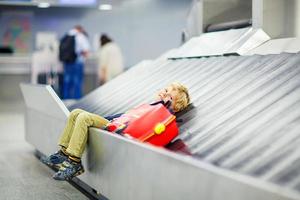 liten trött liten pojke på flygplatsen och reser foto