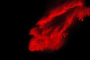 rött pulver explosion på svart bakgrund. frysa rörelse av röda dammpartiklar stänk. foto