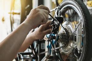 cykelmekaniker reparerar hopfällbar cykel i verkstad. justera bakväxeln, kassettdrevet. cykel underhåll och reparation koncept foto