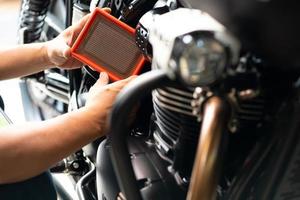 mekaniker håller smutsiga motor luftfilter över motorcykel, skoter .mekaniker arbetar i garage. reparation och underhåll motorcykel koncept foto