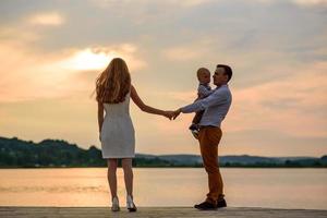 pappa och mamma leder sin ettårige son i handen. foto