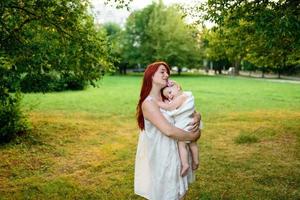 mamma kramar och leker med sin ettåriga dotter inlindad i en handduk efter att ha badat. foto