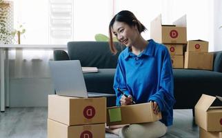 porträtt av asiatisk ung kvinna sm som arbetar med en låda hemma workplace.start-up småföretagare, småföretagare SM eller frilansande företag online och leverans koncept. foto