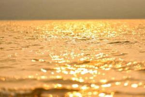 abstrakt solljus reflekterande på vattenbakgrund, lyser bokeh på vattenytan vid solnedgången natur sommar eller vårhav hav foto