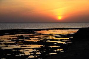 soluppgång på havet med reflektioner på stranden foto