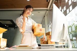 porträtt ung attraktiv asien kvinnlig ägare uppstartsföretag arbeta nöjd med låda hemma förbereda paketleverans i SM-försörjningskedjan, upphandling, online-koncept för omnikanalhandel. foto