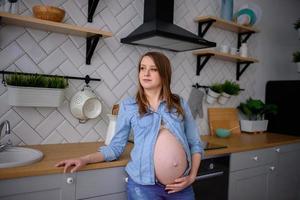 gravid kvinna står i hennes kök foto