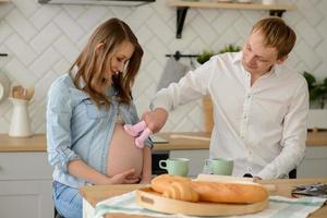 framtida far med sin gravida fru som håller små babystrumpor bredvid sin foto