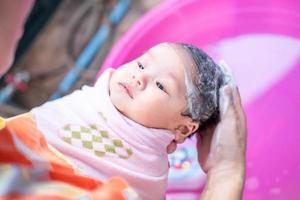 asiatisk mamma dusch baby för att rengöra smuts ge barn i badbehållare för renlighet livsstil familj mellan mor och barn används för baby shower krämprodukter schampon lotioner och babyvårdsprodukter foto