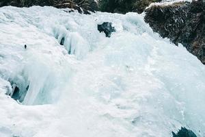 vinter vattenfall med fruset vatten och snö foto