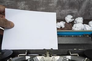 hand som drar en bit vitt papper från en gammal klassisk skrivmaskin. kopieringsutrymme. foto