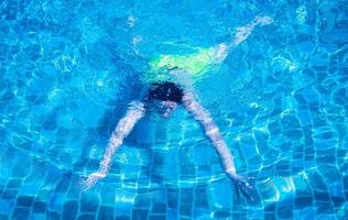 män simmar eller dyker i poolen. ung man tränar eller kopplar av i utomhuspoolen. foto
