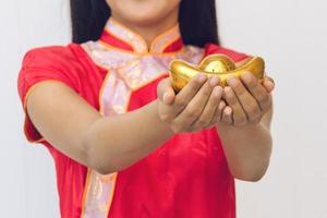 asiatisk kvinna med cheongsam som håller guld. kinesiskt nyår. foto