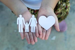 barn händer som håller liten modell av hjärta och familj, koncept familj foto