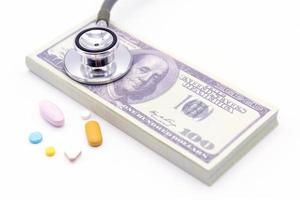 stetoskop med dollar bank och medicin kapslar på vit bakgrund. hälsosam livsstil med affärsekonomi koncept foto